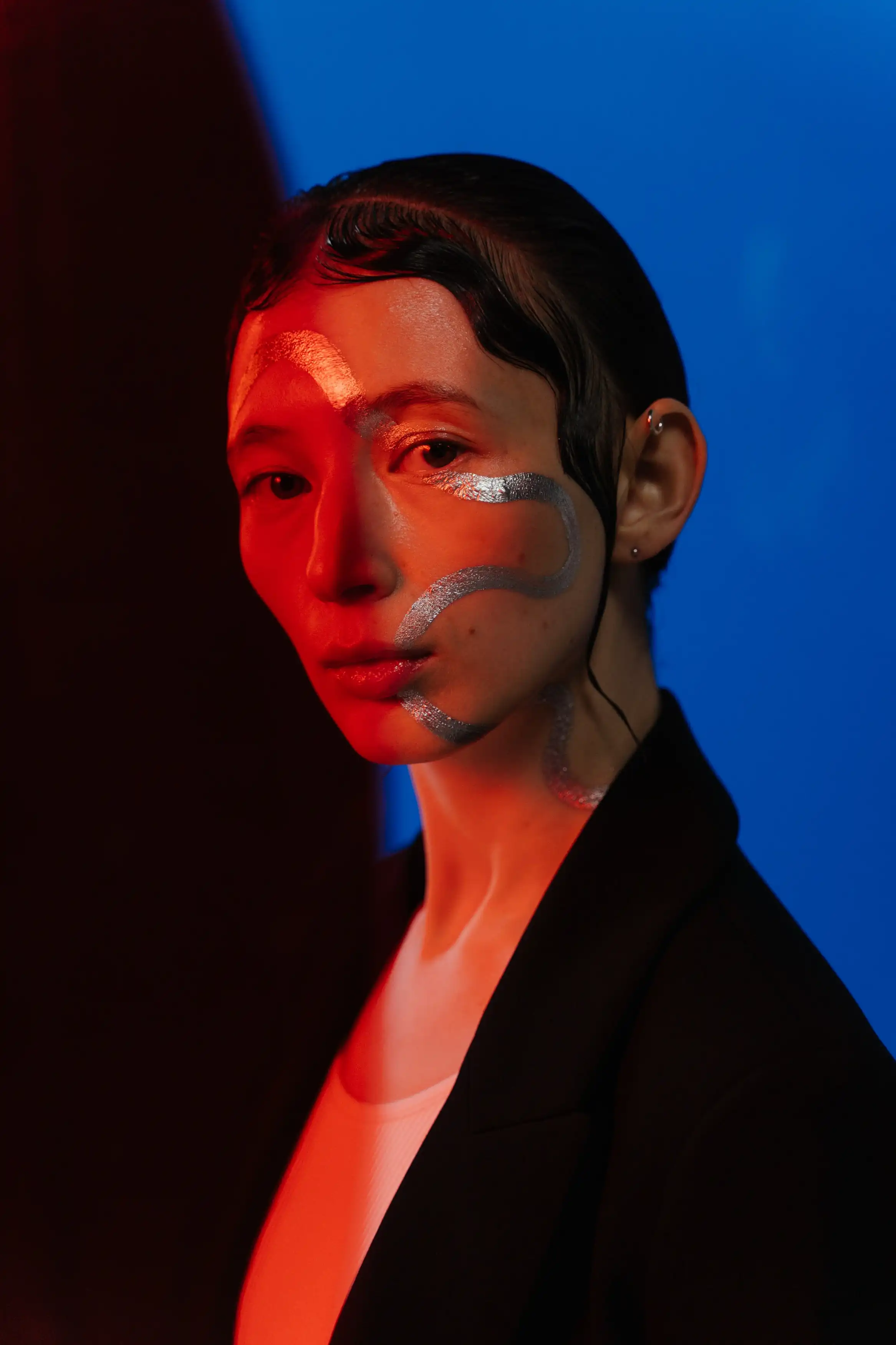 An elegant model like woman, in red and blue light, watching the camera